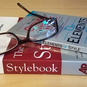 Image of reading glasses sitting on top of the Elements of Style and the AP Stylebook